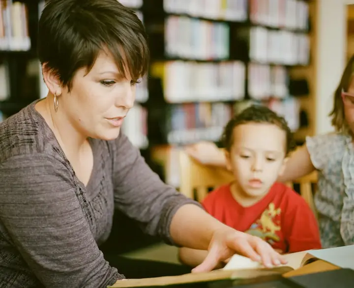 A kindy teacher sharing a picture book with a small group of children